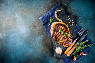 Et ve şarap ahşap kesme tahtası üzerinde çatal ile ızgara biftek dilimlenmiş. Koyu mavi arka plan. Üstten görünüm kopya alanı