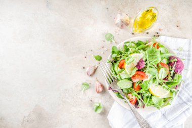 Taze bahar detoks karışımı salata sebze (salatalık, limon, domates, roka ve bebek ıspanak), ışık kayrak, taş veya beton arka plan ile. Üstten görünüm kopya alanı