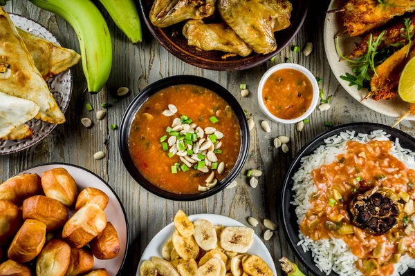 Batı Afrika gıda kavramı. Geleneksel gümüş Afrika yemekleri ürün çeşitliliği - fıstık çorba, jollof pilav, ızgara tavuk kanadı, Kuru kızarmış muz muz, Nijeryalı tavuk kebap, etli turtalar, üstten görünüm