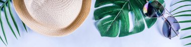 Renkli yaz tatili ve tatil düz-lay. Hasır şapka, güneş gözlüğü, palmiye ve monstera yaprakları parlak mavi sarı arka plan, üstten görünüm, kopya alanı afiş