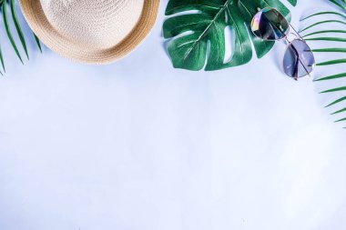 Renkli yaz tatili ve tatil düz-lay. Hasır şapka, güneş gözlüğü, palmiye ve monstera yaprakları parlak mavi sarı arka plan, üstten görünüm, kopya alanı