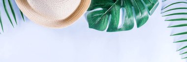 Renkli yaz tatili ve tatil düz-lay. Hasır şapka, güneş gözlüğü, palmiye ve monstera yaprakları parlak mavi sarı arka plan, üstten görünüm, kopya alanı