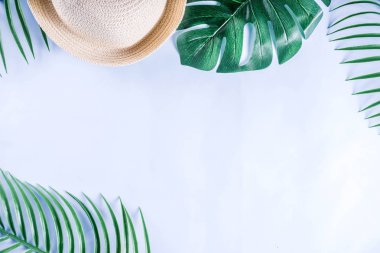 Renkli yaz tatili ve tatil düz-lay. Hasır şapka, güneş gözlüğü, palmiye ve monstera yaprakları parlak mavi sarı arka plan, üstten görünüm, kopya alanı