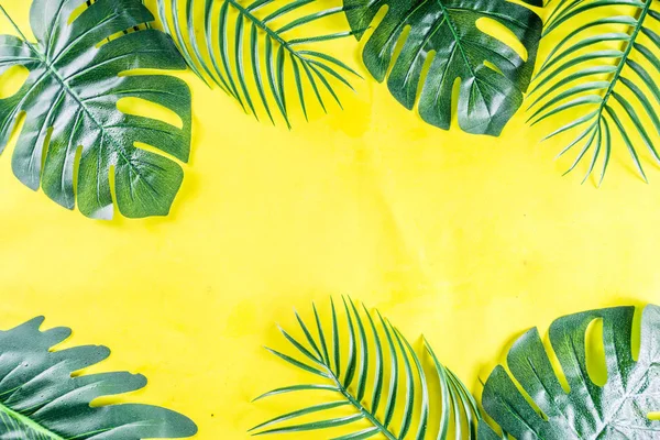 Tropikal arka plan. Palmiye ve monstera yaprakları sarı mavi zemin üzerine. Flatlay, üstten görünüm, minimal düzen, yaz konsepti