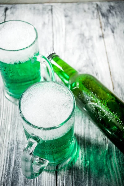 St. Patrick's day concept, two glasses and bottle with cold fresh cold green beer on wooden table, bar counter Background for St. Patrick's day and Oktoberfest menu. Copy space