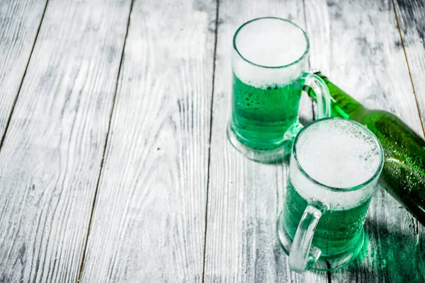 St. Patrick's day concept, two glasses and bottle with cold fresh cold green beer on wooden table, bar counter Background for St. Patrick's day and Oktoberfest menu. Copy space