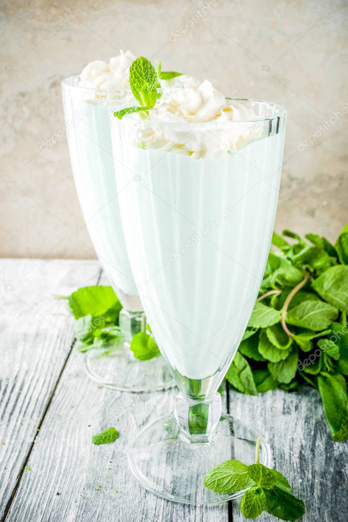 Summer refreshing cocktail, shamrock mint shake, sweet milk drink with fresh mint leaves, wooden background copy space