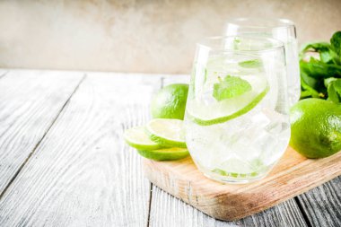 Yaz ekşi içkiyle, kireç ve buz küpleri, kopyalama alanı nane, ev yapımı kokteyl mojito ile taze limes, nane yaprağı, iki bardak, Beyaz ahşap arka plan