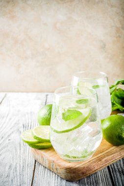 Yaz ekşi içkiyle, kireç ve buz küpleri, kopyalama alanı nane, ev yapımı kokteyl mojito ile taze limes, nane yaprağı, iki bardak, Beyaz ahşap arka plan