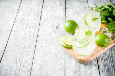 Yaz ekşi içkiyle, kireç ve buz küpleri, kopyalama alanı nane, ev yapımı kokteyl mojito ile taze limes, nane yaprağı, iki bardak, Beyaz ahşap arka plan