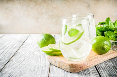 Yaz ekşi içkiyle, kireç ve buz küpleri, kopyalama alanı nane, ev yapımı kokteyl mojito ile taze limes, nane yaprağı, iki bardak, Beyaz ahşap arka plan