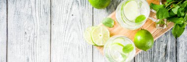Yaz ekşi içkiyle, kireç ve buz küpleri, kopyalama alanı nane, ev yapımı kokteyl mojito ile taze limes, nane yaprağı, iki bardak, Beyaz ahşap arka plan