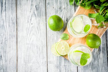 Yaz ekşi içkiyle, kireç ve buz küpleri, kopyalama alanı nane, ev yapımı kokteyl mojito ile taze limes, nane yaprağı, iki bardak, Beyaz ahşap arka plan