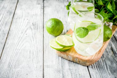 Yaz ekşi içkiyle, kireç ve buz küpleri, kopyalama alanı nane, ev yapımı kokteyl mojito ile taze limes, nane yaprağı, iki bardak, Beyaz ahşap arka plan