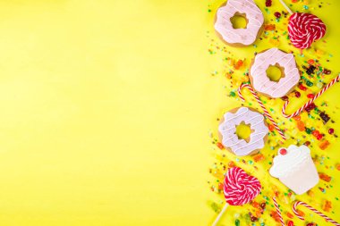 Tatlılar yaratıcı paralamak, lolipop, reçel, şeker, çerezleri çörek ve cupcakes, parlak sarı arka plana üstten görünüm kopya alanı ile tatlı kavramı
