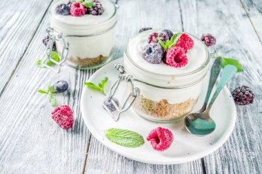 Yaz diyet kahvaltı, sağlıklı sabah tatlı yaz meyveleri - ahududu, yaban mersini, böğürtlen ile alakart kavanozlara Cheesecake tarifi fikirler. Ahşap arka plan kopya alanı üzerinde