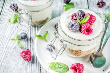 Yaz diyet kahvaltı, sağlıklı sabah tatlı yaz meyveleri - ahududu, yaban mersini, böğürtlen ile alakart kavanozlara Cheesecake tarifi fikirler. Ahşap arka plan kopya alanı üzerinde