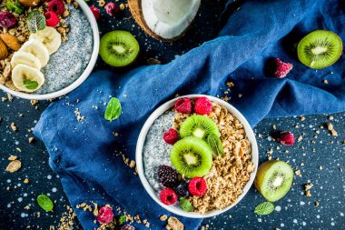 Chia tohum yoğurt puding, taze meyve ve çilek, üzerinde koyu mavi beton arka plan kopya alanı ile ev yapımı granola