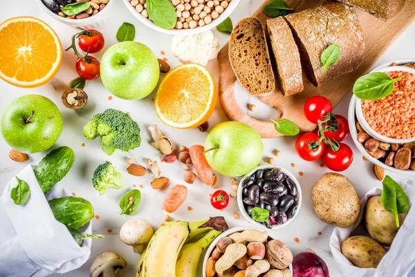 Healthy food. Selection of good carbohydrate sources, high fiber rich food. Low glycemic index diet. Fresh vegetables, fruits, cereals, legumes, nuts, greens. White marble background copy space