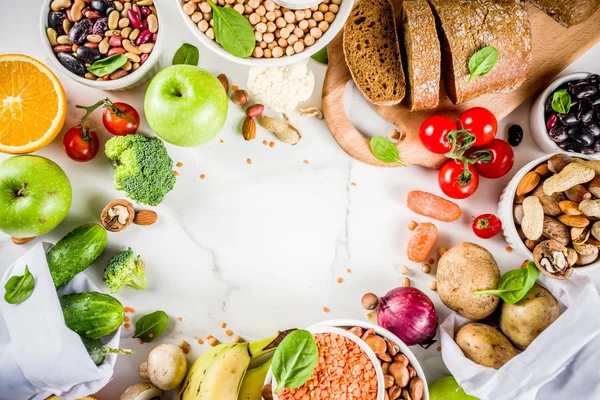 Healthy food. Selection of good carbohydrate sources, high fiber rich food. Low glycemic index diet. Fresh vegetables, fruits, cereals, legumes, nuts, greens. White marble background copy space