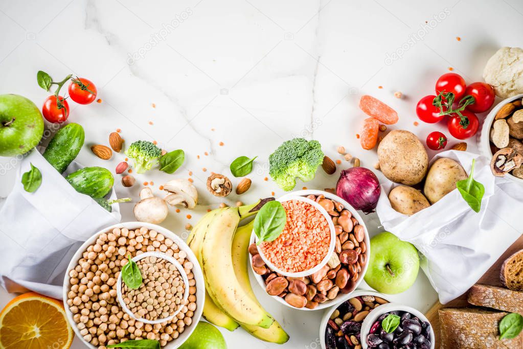 Healthy food. Selection of good carbohydrate sources, high fiber rich food. Low glycemic index diet. Fresh vegetables, fruits, cereals, legumes, nuts, greens. White marble background copy space