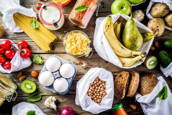 Atık alışveriş ve sustanable yaşam tarzı kavramı, çeşitli çiftlik organik sebzeler, tahıl, makarna, yumurta ve meyve yeniden kullanılabilir ambalaj süpermarket Çantalar sıfır. Kopyalama alanı üstten görünüm, ahşap arka plan