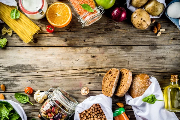 Zero waste shopping and sustanable lifestyle concept, various farm organic vegetables, grains, pasta, eggs and fruits in reusable packaging supermarket bags. copy space top view, wooden background