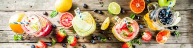 Çeşitli meyve ve meyve limonata içecekler, ferahlık infüzyon seçimi, su taze çilek, limon, limon, portakal, yaban mersini, mason kavanoz ahşap arka plan kopya alanı