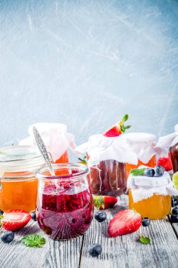 Kavanoz ahşap masa üzerinde çeşitli mevsimlik berry ve meyve sıkışmaları. Kopya alanı