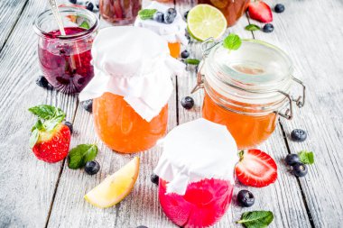 Kavanoz ahşap masa üzerinde çeşitli mevsimlik berry ve meyve sıkışmaları. Kopya alanı