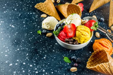Renkli meyve ve berry, fındık, çikolata ve vanilyalı dondurma, taze meyve ve çilek, üstten görünüm kopya alanı koyu mavi arka plan ile gözleme Ice - cream koniler ile