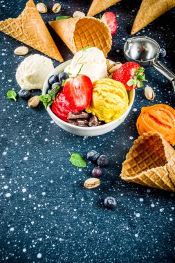 Renkli meyve ve berry, fındık, çikolata ve vanilyalı dondurma, taze meyve ve çilek, üstten görünüm kopya alanı koyu mavi arka plan ile gözleme Ice - cream koniler ile