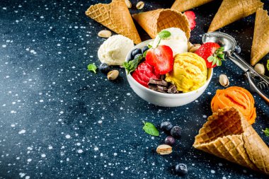 Renkli meyve ve berry, fındık, çikolata ve vanilyalı dondurma, taze meyve ve çilek, üstten görünüm kopya alanı koyu mavi arka plan ile gözleme Ice - cream koniler ile