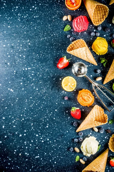 Renkli meyve ve berry, fındık, çikolata ve vanilyalı dondurma, taze meyve ve çilek, üstten görünüm kopya alanı koyu mavi arka plan ile gözleme Ice - cream koniler ile