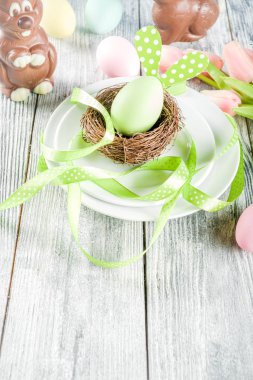 Paskalya tatili sofra tavşan ve yumurta, renkli yumurta ve çikolata bunny tavşan, şenlikli şerit, ahşap arka plan üstten görünüm kopya alanı ile plakalar ile