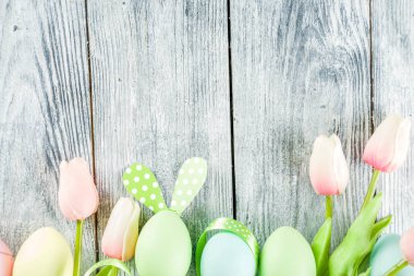 Paskalya tatili sofra tavşan ve yumurta, renkli yumurta ve çikolata bunny tavşan, şenlikli şerit, ahşap arka plan üstten görünüm kopya alanı ile plakalar ile