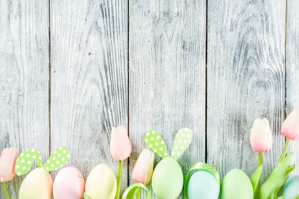 Paskalya tatili sofra tavşan ve yumurta, renkli yumurta ve çikolata bunny tavşan, şenlikli şerit, ahşap arka plan üstten görünüm kopya alanı ile plakalar ile