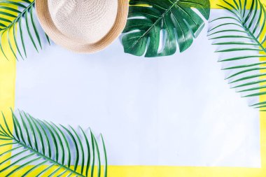 Renkli yaz tatili ve tatil düz-lay. Hasır şapka, güneş gözlüğü, palmiye ve monstera yaprakları parlak mavi sarı arka plan, üstten görünüm, kopya alanı