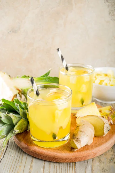 Healthy and immunity diet drink. Ginger and pineapple cold tea, infused water, Wooden background copy space