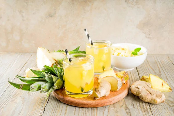 Healthy and immunity diet drink. Ginger and pineapple cold tea, infused water, Wooden background copy space