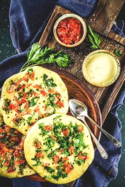 Indian traditional food recipes, Uttapam oats or semolina pancakes with fresh vegetables and herbs, dark blue background copy space top view