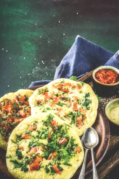 Indian traditional food recipes, Uttapam oats or semolina pancakes with fresh vegetables and herbs, dark blue background copy space top view