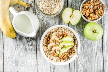 Sağlıklı kahvaltı fındık reklam meyve - elma, muz, ceviz, ahşap arka plan kopya alanı üzerinde Sütlü yulaf ezmesi