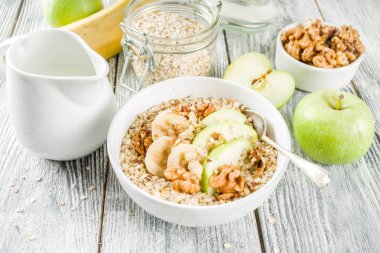 Sağlıklı kahvaltı fındık reklam meyve - elma, muz, ceviz, ahşap arka plan kopya alanı üzerinde Sütlü yulaf ezmesi