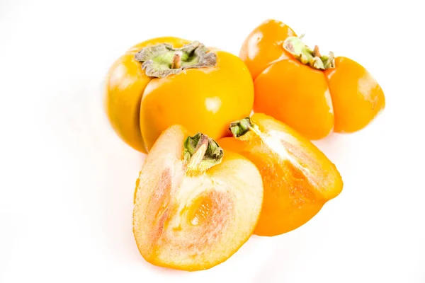 Persimmons inteiros e fatiados em branco — Fotografia de Stock