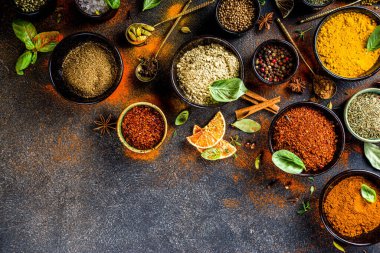Pişirmek için baharat ve ot seti. Renkli baharatlı küçük kaseler fesleğen, biber, safran, tuz, paprika, zerdeçal. Siyah taş tablo üzerinde üst görünüm kopyalama alanı