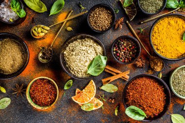 Pişirmek için baharat ve ot seti. Renkli baharatlı küçük kaseler fesleğen, biber, safran, tuz, paprika, zerdeçal. Siyah taş tablo üzerinde üst görünüm kopyalama alanı