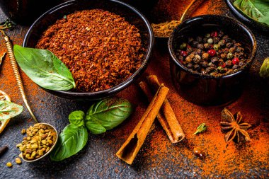 Pişirmek için baharat ve ot seti. Renkli baharatlı küçük kaseler fesleğen, biber, safran, tuz, paprika, zerdeçal. Siyah taş tablo üzerinde üst görünüm kopyalama alanı