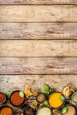 Pişirmek için baharat ve ot seti. Renkli baharatlı küçük kaseler fesleğen, biber, safran, tuz, paprika, zerdeçal. Kırsal ahşap masa arka planında, üst görünüm kopyalama alanı