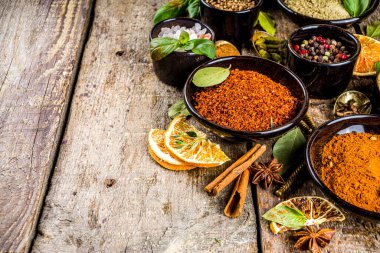 Pişirmek için baharat ve ot seti. Renkli baharatlı küçük kaseler fesleğen, biber, safran, tuz, paprika, zerdeçal. Kırsal ahşap masa arka planında, üst görünüm kopyalama alanı